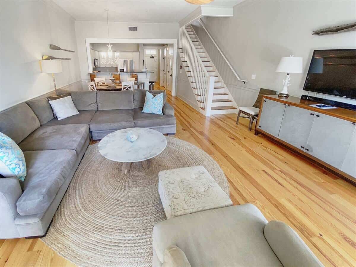 A living room with a sectional sofa, a round coffee table, a rug, a TV, and a staircase.