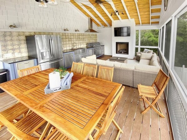 Una mesa de comedor de madera con sillas, una cocina con electrodomésticos de acero inoxidable y una chimenea.