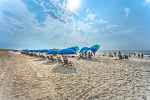 A beach with rows of blue umbrellas and beach chairs.