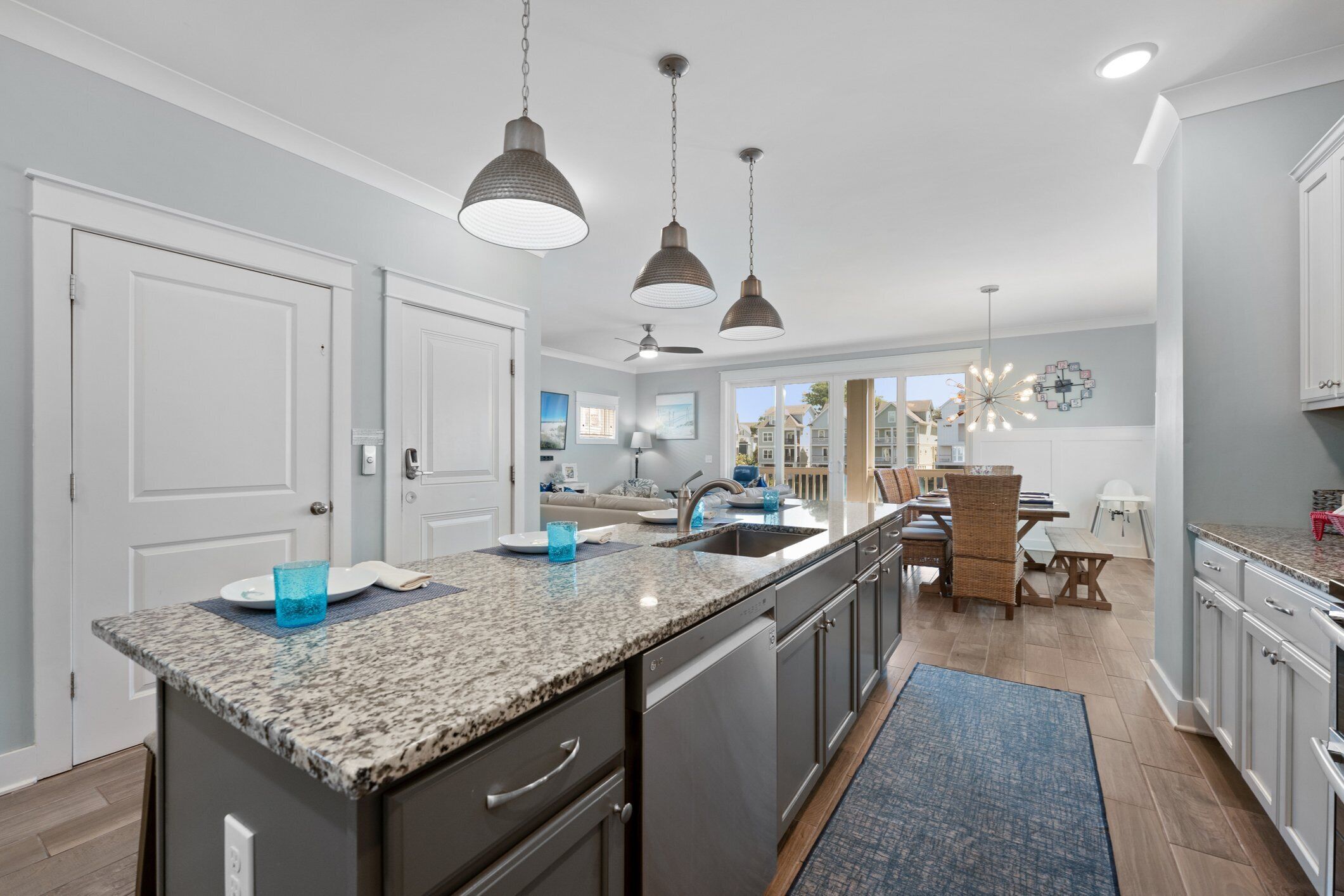 A modern kitchen with granite countertops, stainless steel appliances, and pendant lighting.