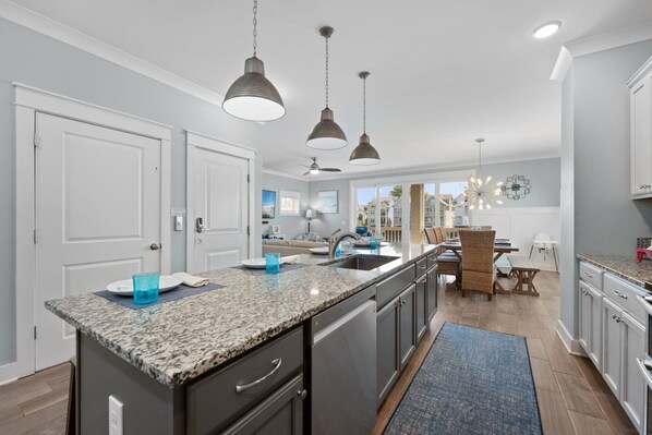 A modern kitchen with granite countertops, stainless steel appliances, and pendant lighting.