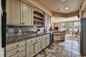 Cocina con encimeras de granito, gabinetes de madera y salpicadero de piedra.