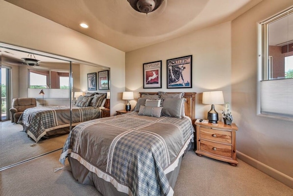 A bedroom with a large mirror, two beds with matching bedding, bedside tables with lamps, and framed pictures on the wall.