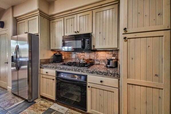 A kitchen with wooden cabinets, a stainless steel refrigerator, a microwave, a stove, and a dishwasher.