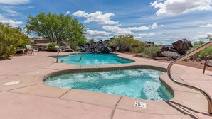 Una piscina con hidromasaje, rodeada de sillones de descanso y un paisaje rocoso.