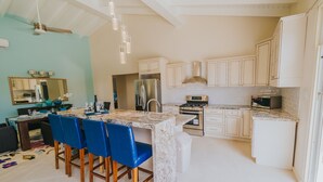 A modern kitchen with white cabinets, a marble island, blue chairs, and stainless steel appliances. - 5 BDR, 6 BATH LUXURY VILLA WALK TO RITZ , MARRIOTT & PALM BEACH (Noord)