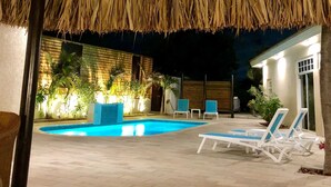 An outdoor pool area with lounge chairs and a thatched roof structure. - 5 BDR, 6 BATH LUXURY VILLA WALK TO RITZ , MARRIOTT & PALM BEACH (Noord)