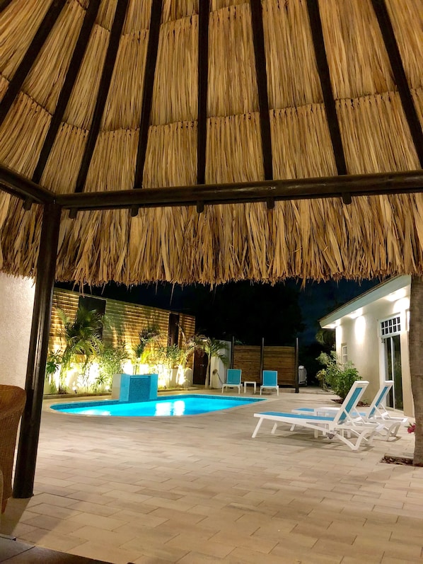 An outdoor pool area with lounge chairs and a thatched roof structure. - 5 BDR, 6 BATH LUXURY VILLA WALK TO RITZ , MARRIOTT & PALM BEACH (Noord)