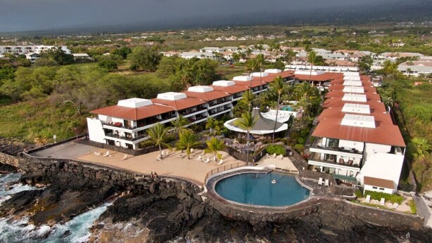 A resort with a pool, multiple buildings, and a rocky coastline. - Oceanfront complex at Casa De Emdeko unit #130 (Kailua-Kona)
