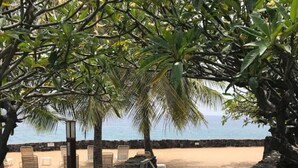 A pathway leading to a beach with a view of the ocean, surrounded by palm trees and a stone wall. - Oceanfront complex at Casa De Emdeko unit #130 (Kailua-Kona)
