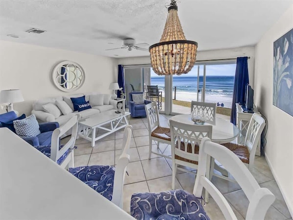 A beachside living area with a sofa, chairs, a table, and a view of the ocean. - Gulf Front Views-Beach Chairs*-Ground Floor BMV 4B (Santa Rosa Beach)
