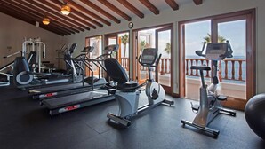 Un gimnasio con cintas de correr, elípticas y bicicletas estáticas, con amplias ventanas y vistas al océano.