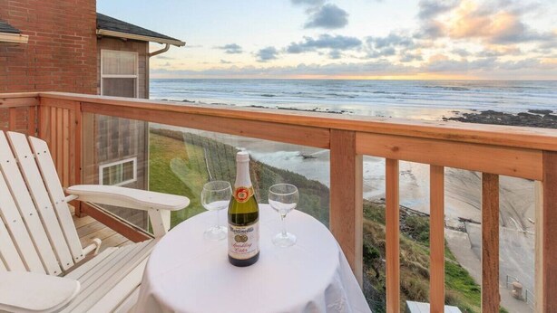 Un balcón con una mesa lista para dos personas, con vista a la playa.