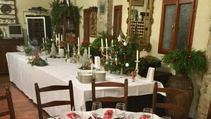 Una mesa de comedor dispuesta para una comida, con manteles blancos, servilletas rojas y un centro de mesa con plantas y adornos rojos.