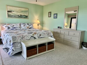 Une chambre à coucher avec un lit, une commode, un banc et un tableau accroché au mur.