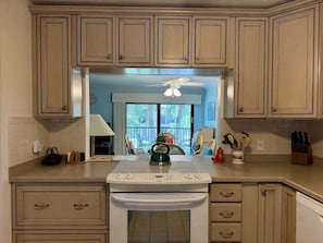 Une cuisine avec des meubles de couleur beige, une cuisinière blanche et un coin repas comprenant des chaises et une table.