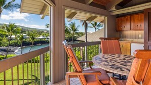 Un área de comedor al aire libre techada con vista a una playa y palmeras.