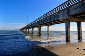 A pier extending into the water with a clear sky above.