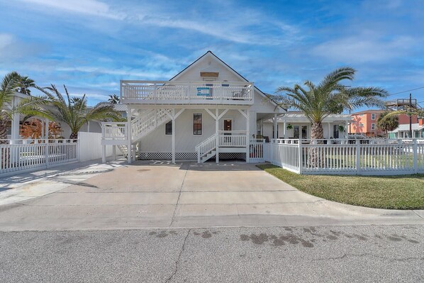 A two-story house with a balcony, a covered porch, and a fenced yard.