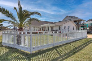 A house with a covered porch, a fenced yard, and a palm tree.