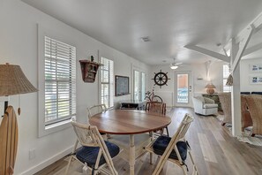 A dining area with a wooden table and chairs, a sail wheel decoration, and a bicycle in the background.