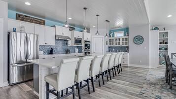 Cozinha moderna com ilha central, armários brancos e painel de fundo azul.