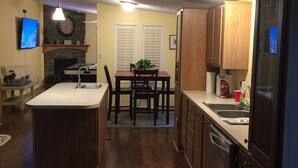 A kitchen with a central island, wooden cabinets, a built-in oven, and a dining area with a table and chairs. - Country Living with a Twist (Bolivia)