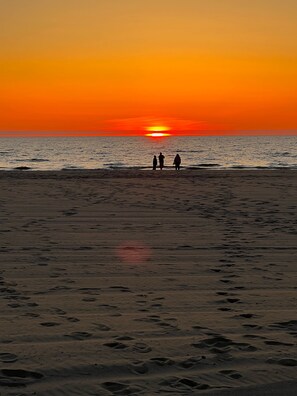 Una spiaggia al tramonto con impronte sulla sabbia.
