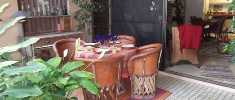Un espace de restauration en plein air avec une table dressée pour quatre personnes, entourée de chaises en osier.