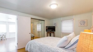 Ein Schlafzimmer mit einem Bett, einem Fernseher und einem Fenster mit Jalousien.