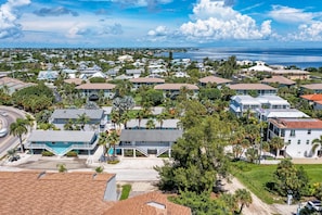 Una zona residencial costera con casas, una carretera y un puente a lo lejos.