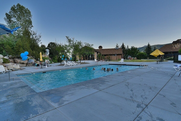 A swimming pool with lounge chairs and a small building in the background.