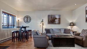 Un salon comprenant un canapé, une table basse et des fauteuils, un coin repas avec une table et des chaises, et des œuvres d’art accrochées aux murs.