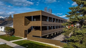 Un bâtiment moderne doté d’une façade en bois, de plusieurs étages et d’un escalier menant à l’entrée.