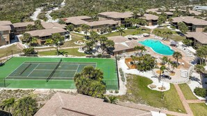 Una zona residencial con varias casas de dos pisos, una cancha de tenis y una piscina.