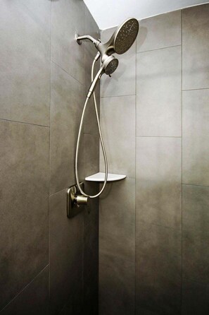 Eine moderne Dusche mit Handbrause und Armaturen an der Wand.