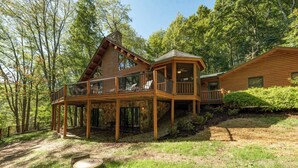 Une cabane dotée d’une terrasse en bois, d’un porche couvert et de fondations en pierre.