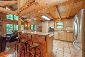 Cozy cabin interior with a high ceiling, wooden beams, and a fireplace.