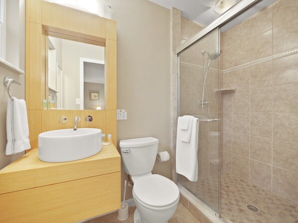 A bathroom with a sink, toilet, and glass-enclosed shower.
