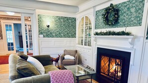 Una sala de estar con chimenea, un sofá, una mesa de centro de vidrio y una estatua decorativa de un ciervo.