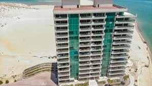 A high-rise hotel with multiple balconies, situated by a beach with a clear view of the ocean. - Tessoro 703 - Award Winning Design at the End of Las Conchas (Puerto Penasco/Rocky Point)