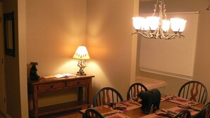 Un comedor con una mesa de madera, sillas, una lámpara y una araña.