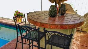 Un bar junto a la piscina con dos sillas y dos jarrones decorativos.