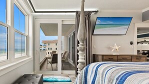 Un dormitorio con una cama grande, vista a la playa, un balcón y un televisor en la pared.