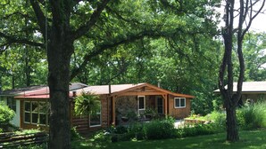 A rustic cabin with a stone foundation, wooden exterior, and a porch with a railing.