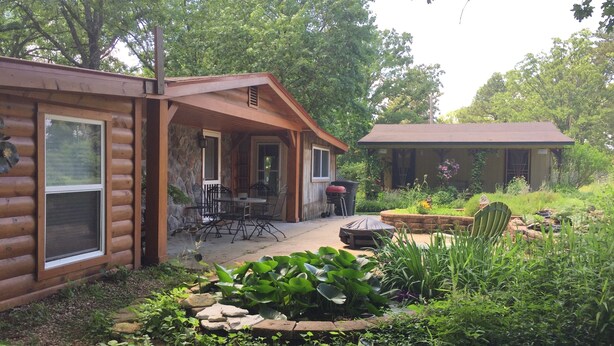 A log cabin with a patio area featuring outdoor furniture and a garden.