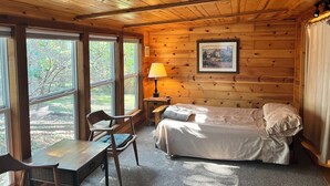 A cozy cabin room with a bed, a desk, and a chair.