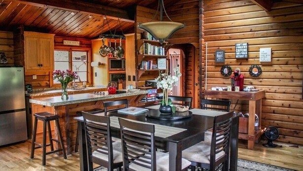 A rustic cabin interior with a wooden dining area, kitchen, and a bookshelf. - ✨Rustic Cabin in Dry Creek Valley with beautiful views // 5 miles to Plaza ✨ (Healdsburg)