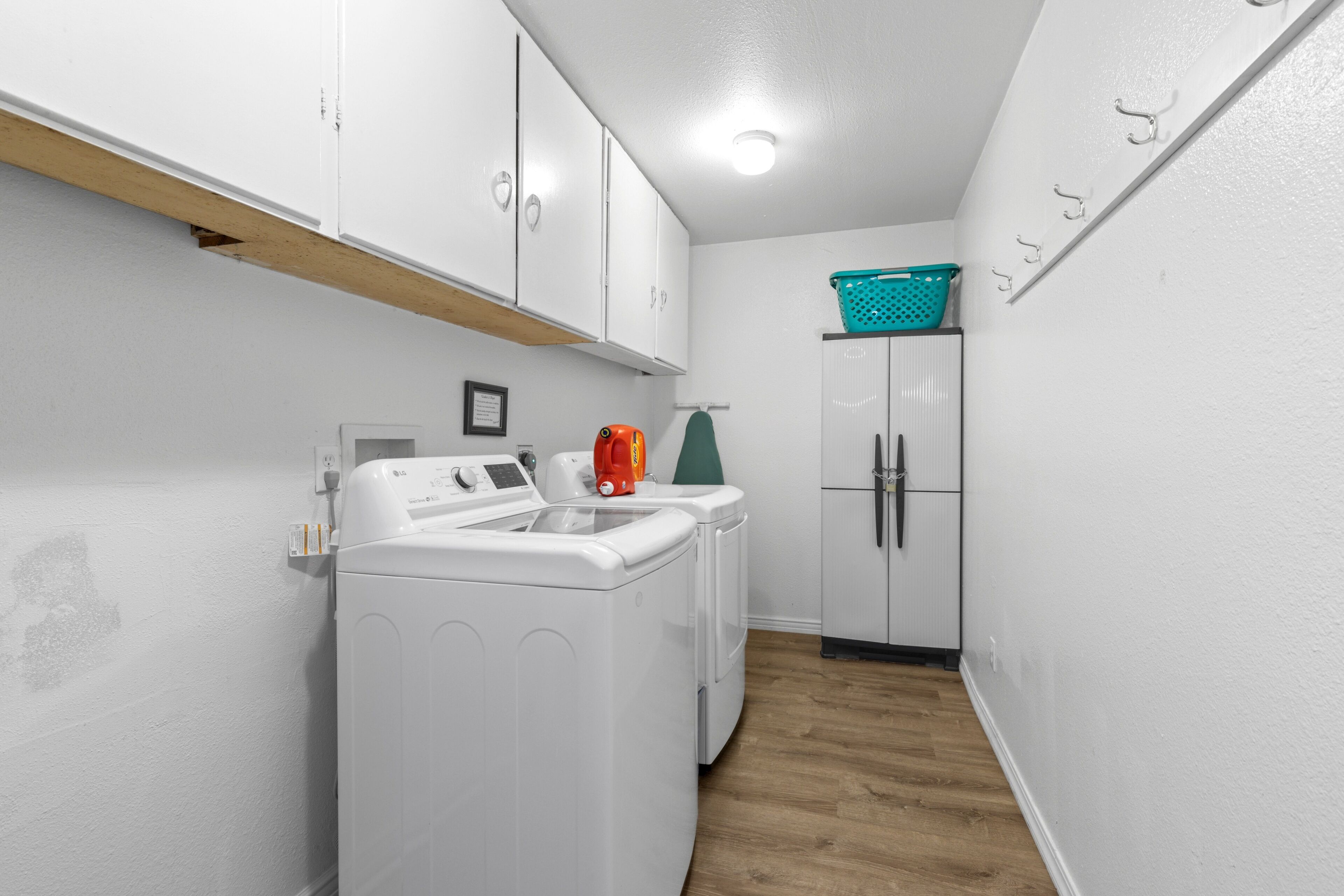 A laundry room with a washing machine, dryer, and a cabinet with a basket on top.
