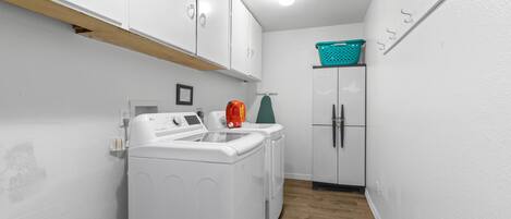 A laundry room with a washing machine, dryer, and a cabinet with a basket on top.